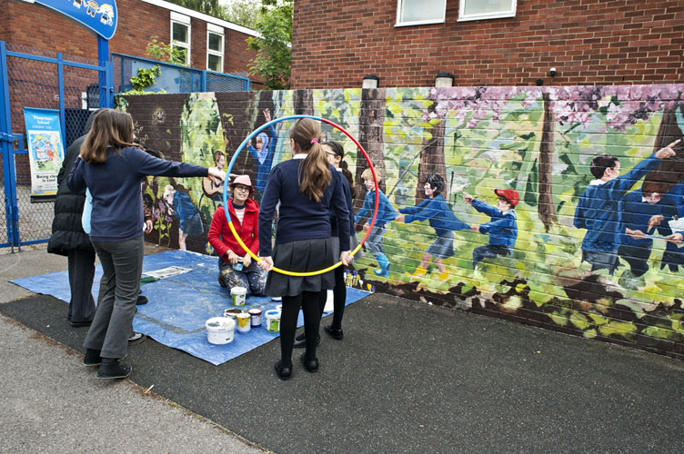 school kids watch mural artist